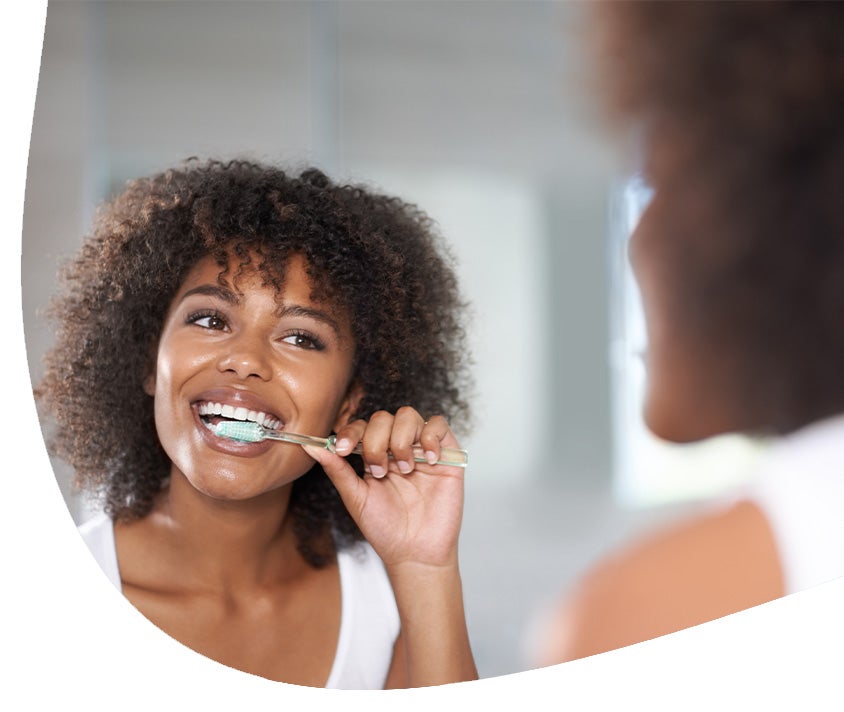 A woman brushing her teeth to manage gum recession