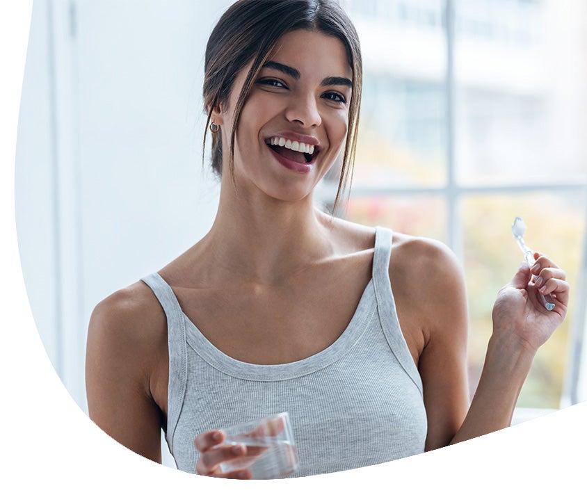 A woman smiling after completing her daily oral care routine